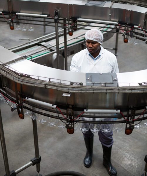 Factory engineer monitoring a production line Factory engineer monitoring a production line in drinks production plant